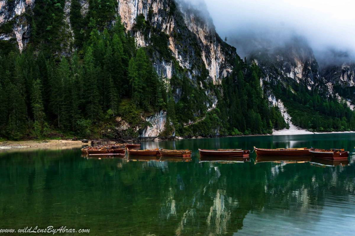 Reflection of the boats and mountains on the calm waters of Lago di Braies